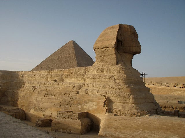 Sfinga, v pozadí pyramída v Gíze.